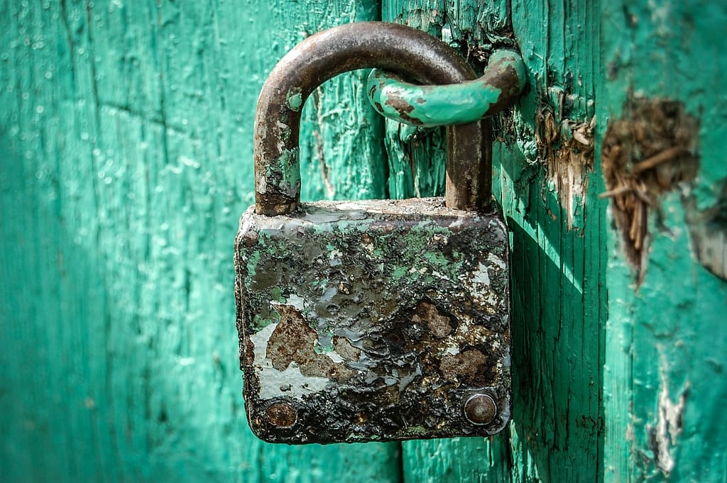 Strong padlock on a teal colored door.