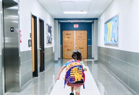Student wearing a backpack running down a school hallway